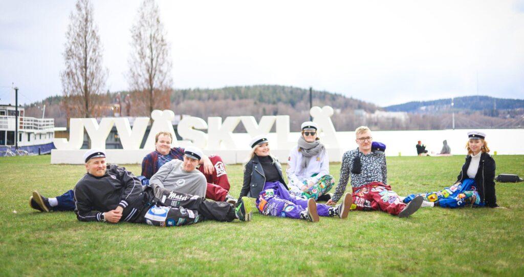 Opiskelijat istuu Jyväskylä-kyltin luona