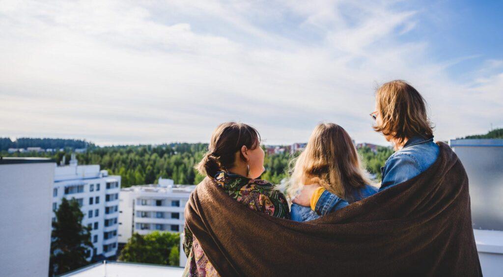 Kolme ihmistä katselee ylioppilaskylää katolla.