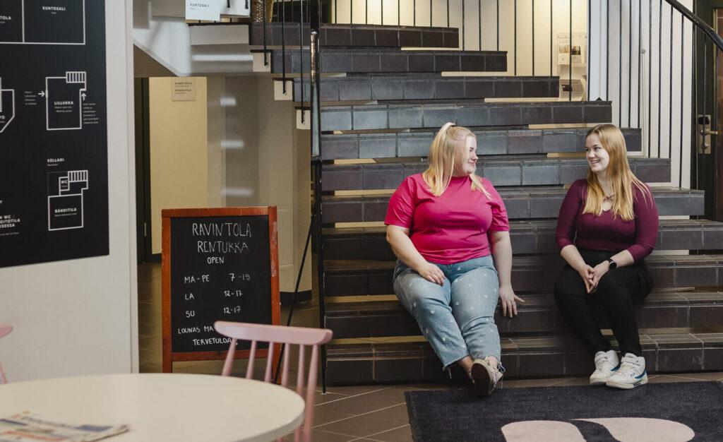 Kaksi opiskelijaa istumassa Rentukan portailla.